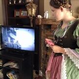 Picture of girl in Shakespearean era costume playing a video